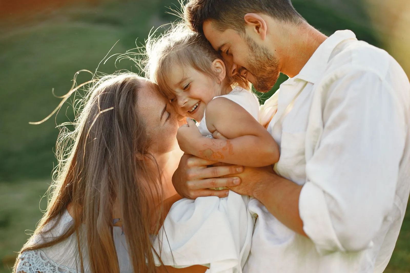 Parents embracing their laughing toddler in warm sunlight — the family-centered care Evolve Health brings to Denton